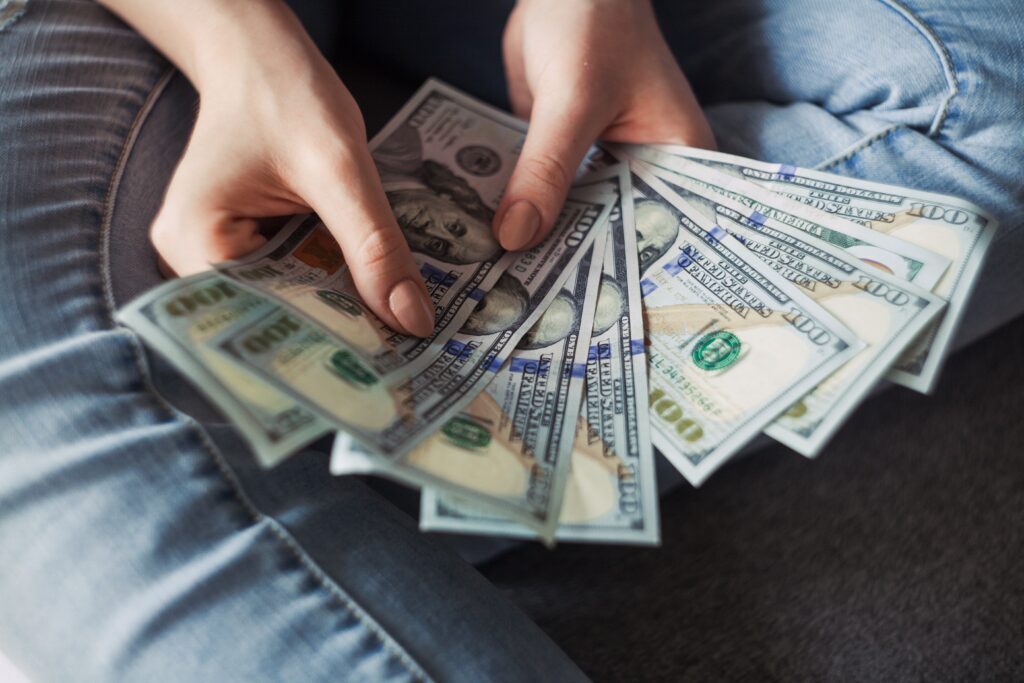 person holding hundreds of dollars fanned out